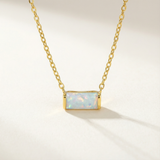 Gold necklace with a rectangular opal pendant on a light background