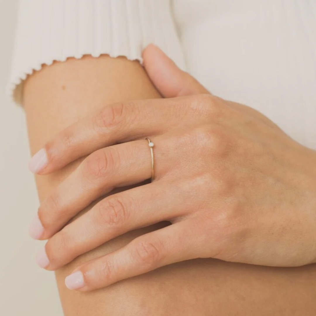 a stylish women wearing a dainty opal ring on her middle finger