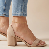 A women wearing a gold satellite anklet paired with beige heels