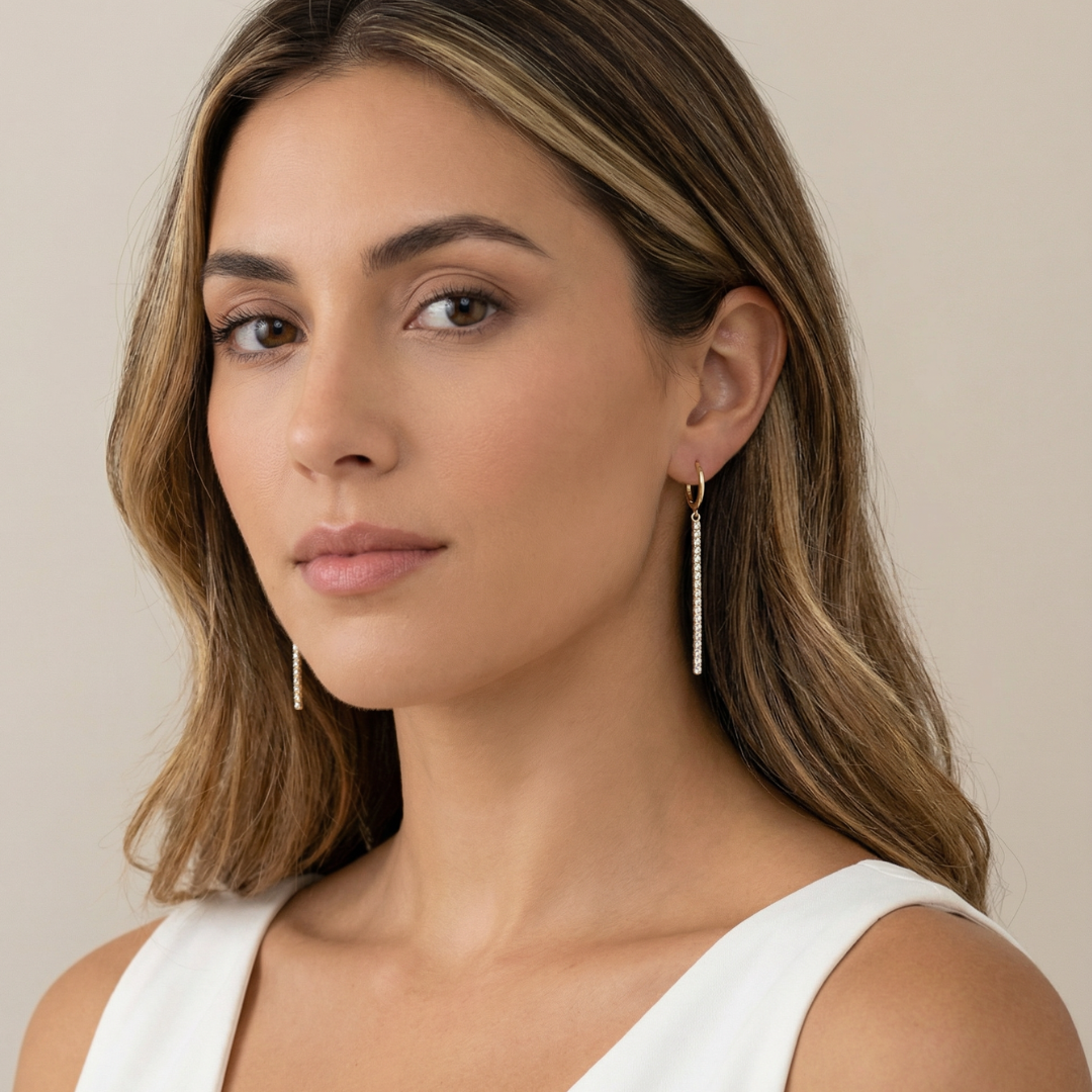 Woman wearing gold earrings for a wedding against a neutral background