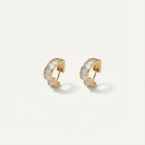 Gold hoop earrings with clear stones on a light beige background
