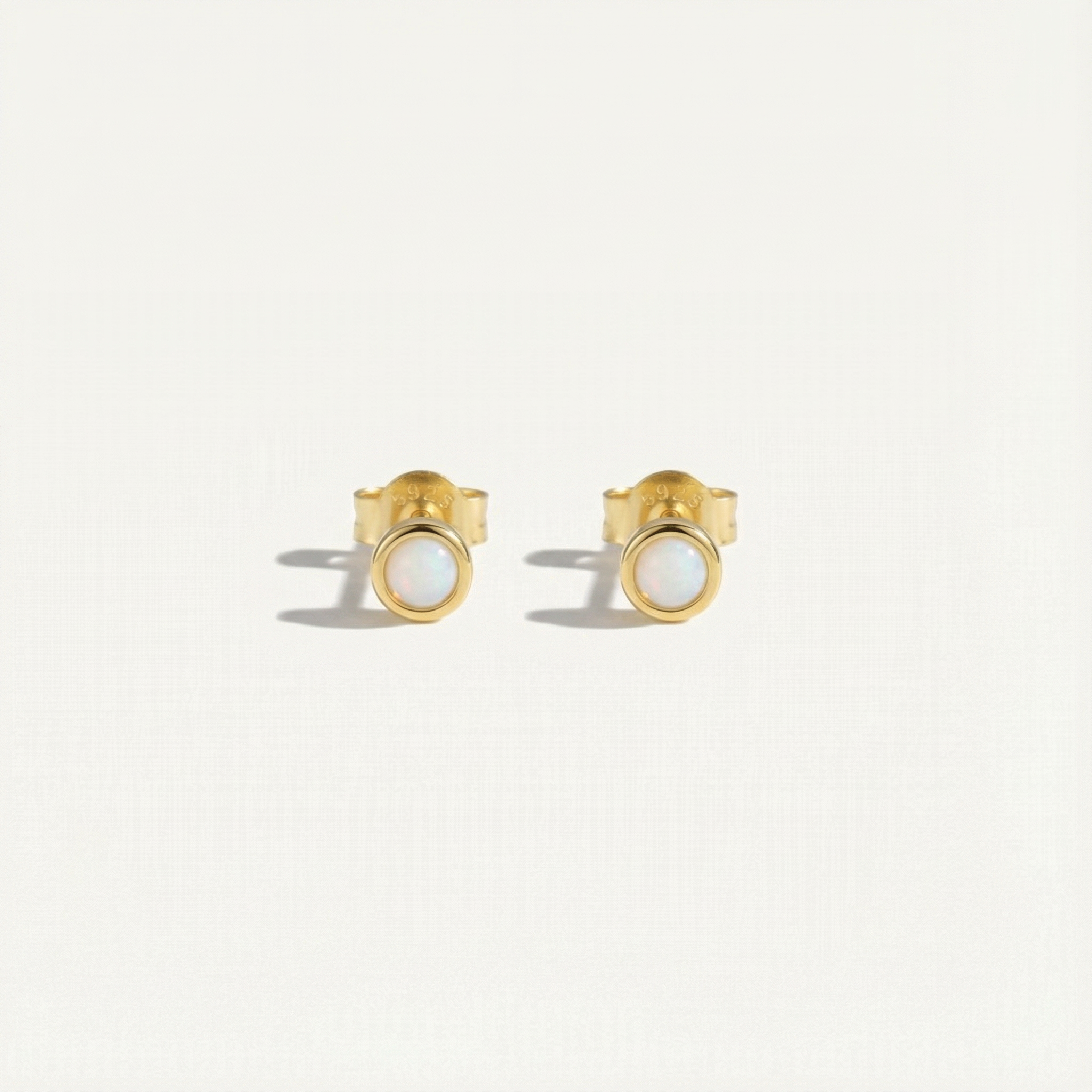 Gold opal stud earrings with gemstones on a light gray background