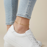Gold anklet on a person's ankle with white sneakers and light blue jeans.