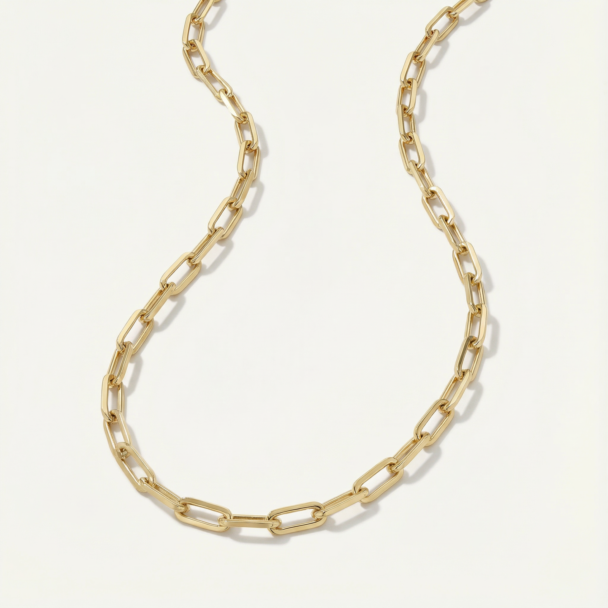 Gold paperclip necklace on a light gray background