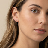 Close-up of a woman wearing a pearl stud earring against a neutral background
