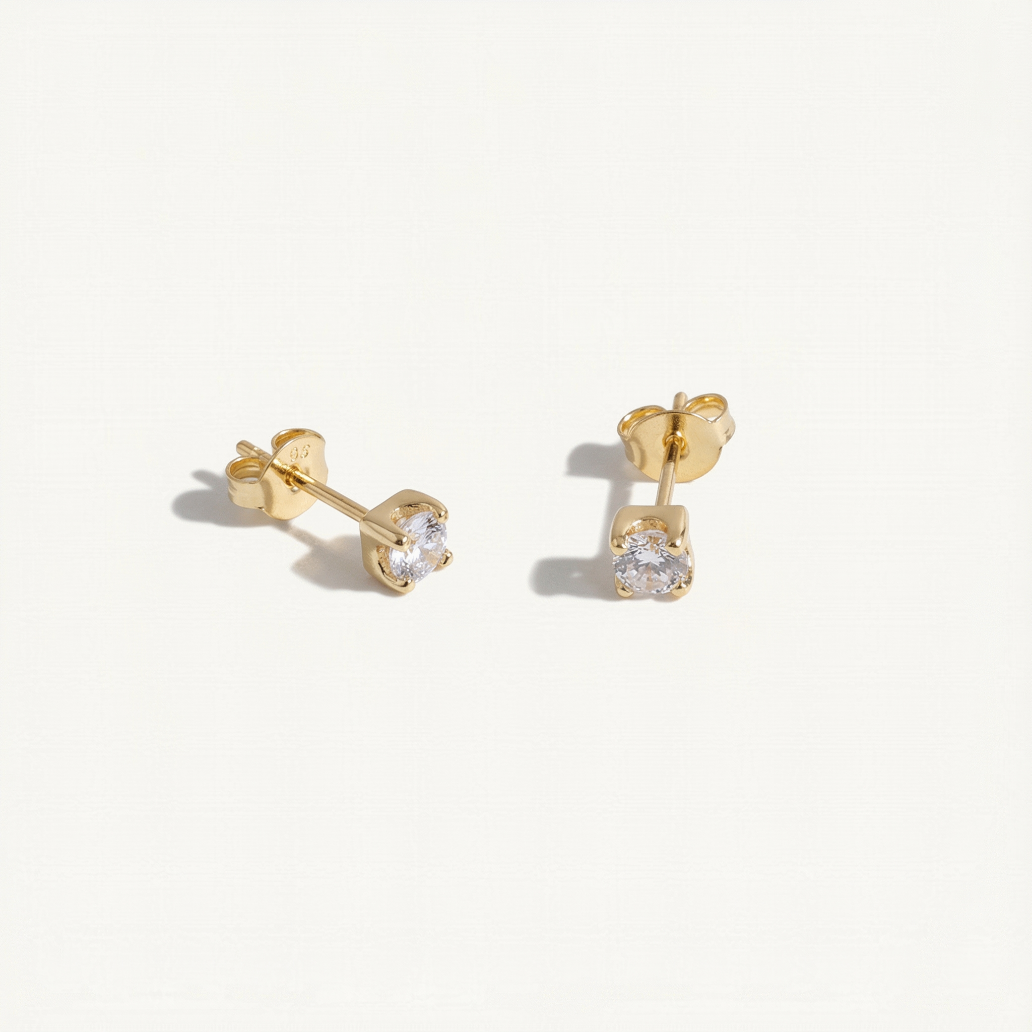 Gold stud earrings with clear gemstones on a white background
