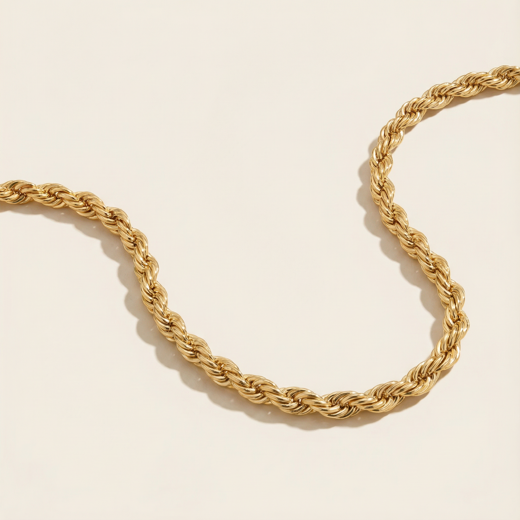 Gold rope chain necklace on a beige background
