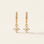Gold earrings with opal stones on a beige background