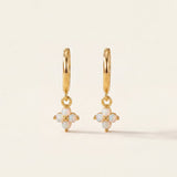 Gold earrings with opal stones on a beige background