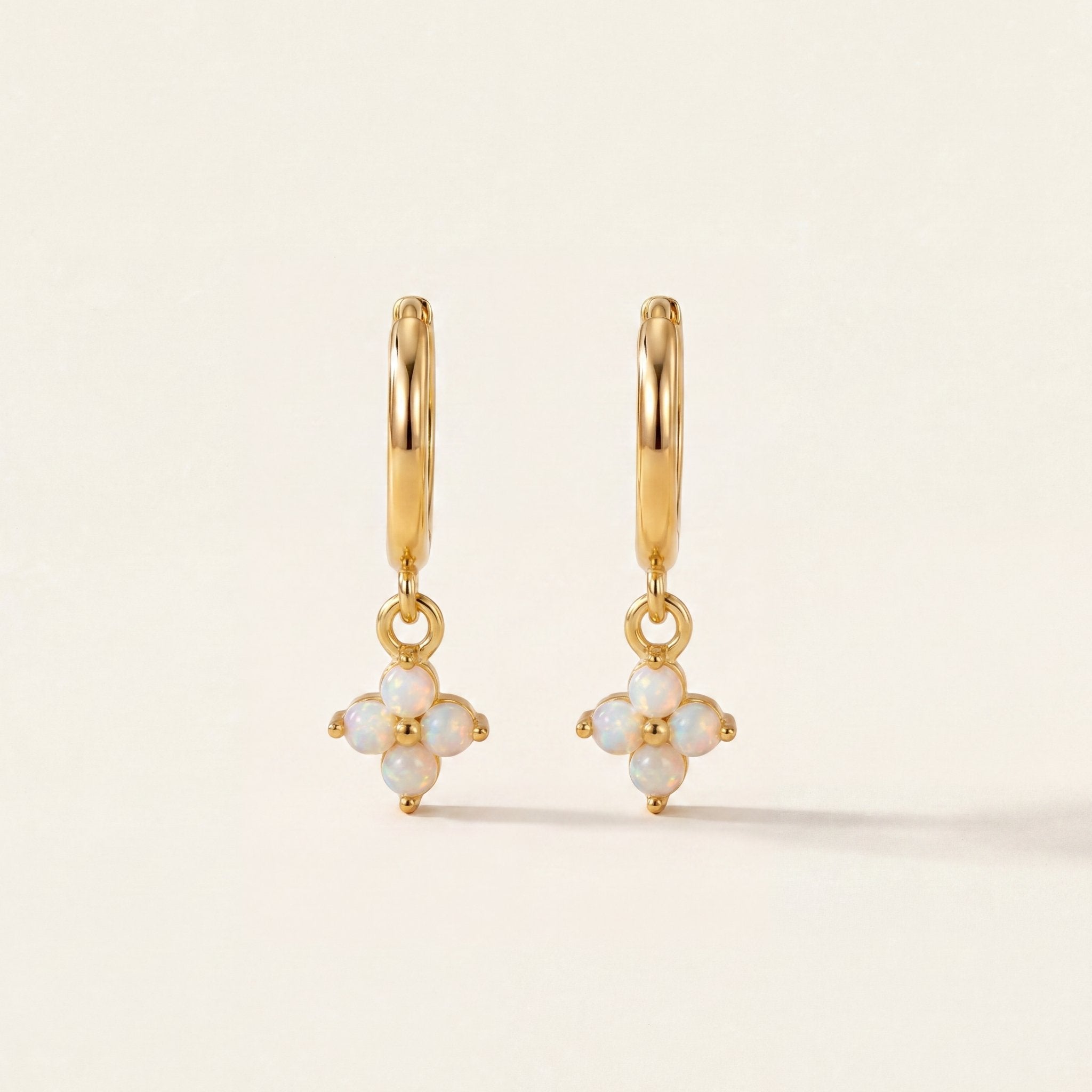 Gold earrings with opal stones on a beige background