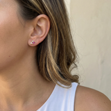 Close-up of a person wearing a pink sdainty earring with a neutral background