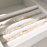 twelve stackable gold rings laying in a jewelry display