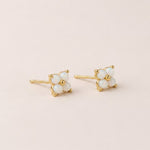 opal stud earrings with the opal gemstones in the shape of a flower on a beige background