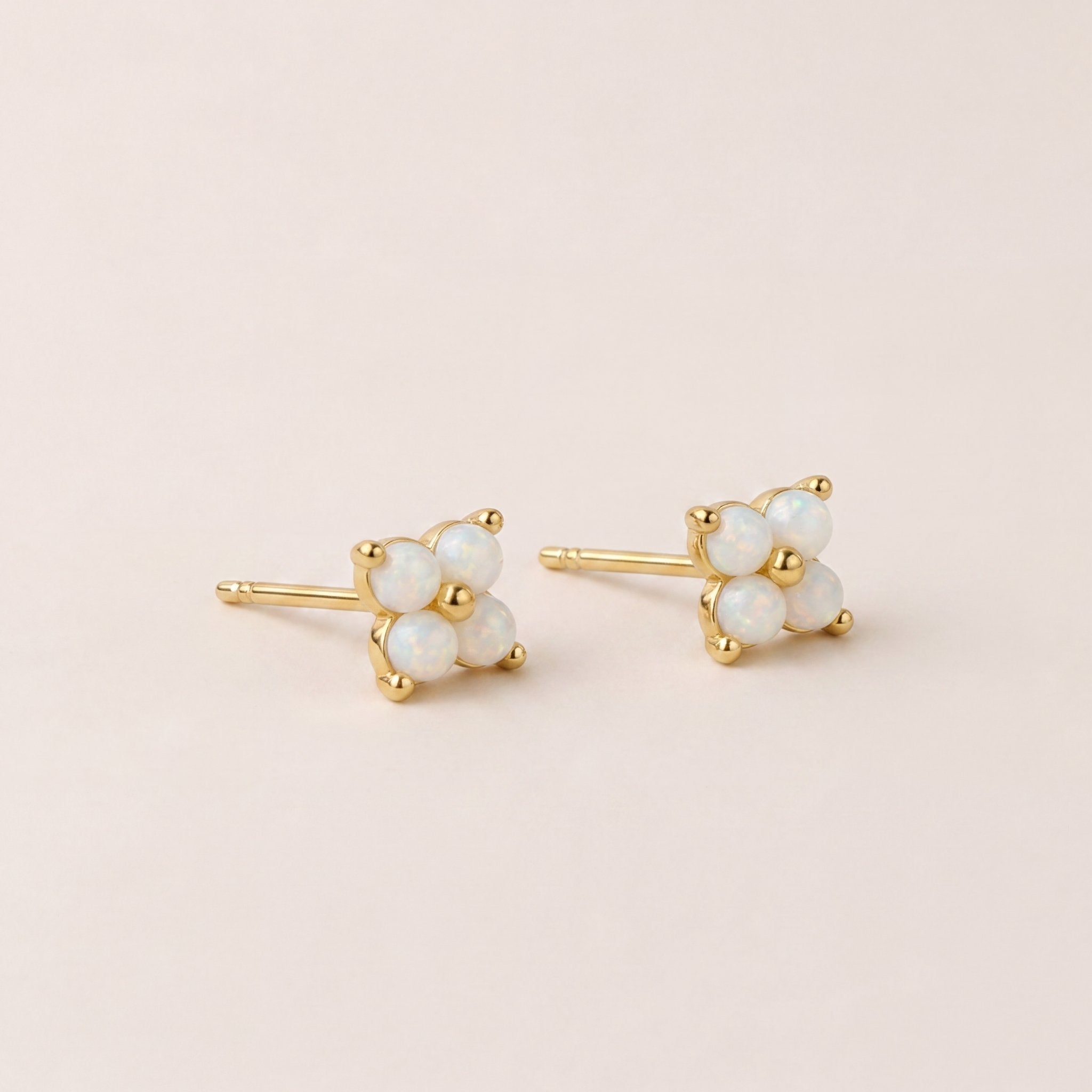 opal stud earrings with the opal gemstones in the shape of a flower on a beige background