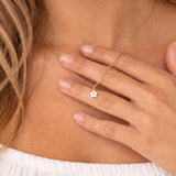 model wearing dainty gold necklace with white enamel flower pendant