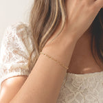Woman wearing the Figaro Bracelet, an 18k gold filled flat chain bracelet by Kate Gates Jewelry